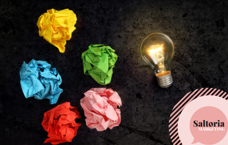 An image of a lit up light bulb and 5 colourful scrunched up pieces of paper - image depicting a lack of ideas.