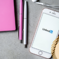 A smart phone with the LinkedIn logo next to some stationary - a LinkedIn for small business workspace. Saltoria Marketing logo on the bottom right
