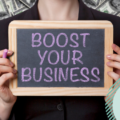 Girl holding balckboard. Text on blackboard reads "boost your business". The picture reflects the title of the blog "14 tips for small business marketing"